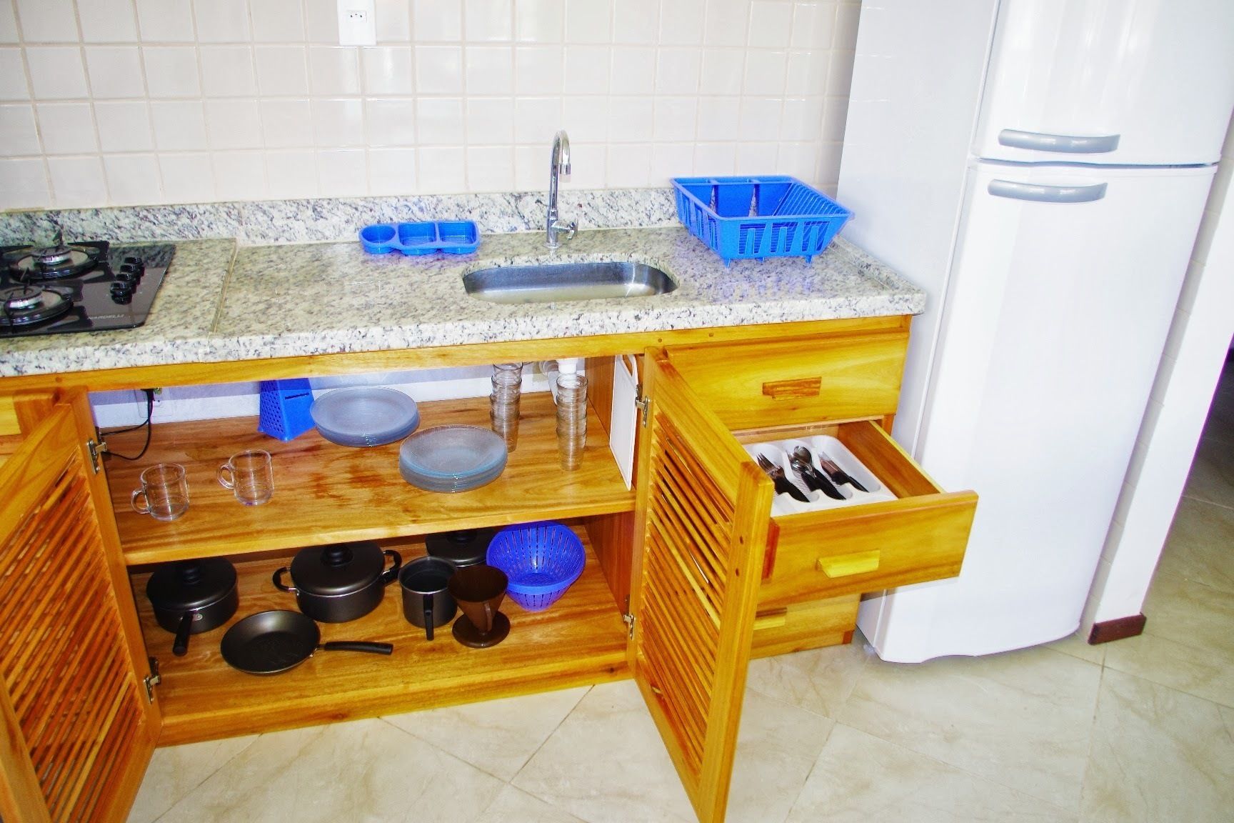 A kitchen with a granite countertop, a sink, a stove, and a white refrigerator.