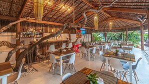 An outdoor restaurant with thatched roofs, wooden tables, and chairs. - Village Mutà (Porto Seguro)