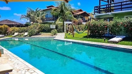 Una piscina al aire libre, sombrillas, sillones reclinables de piscina