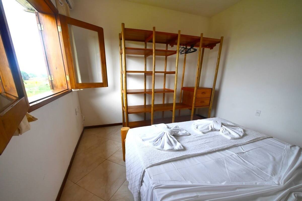 A room with a bunk bed, a small wooden shelf, a mirror, and a window.