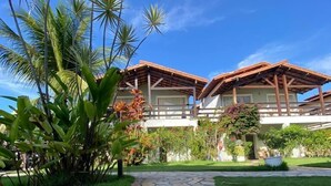 A pathway leading to a building with a tiled roof and a garden with palm trees. - Village Mutà (Porto Seguro)