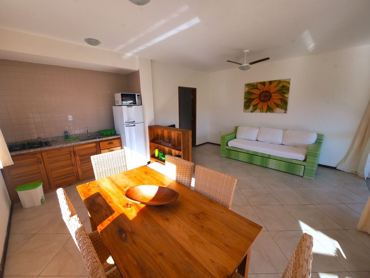 A dining area with a wooden table and chairs, a green sofa, and a kitchen in the background.