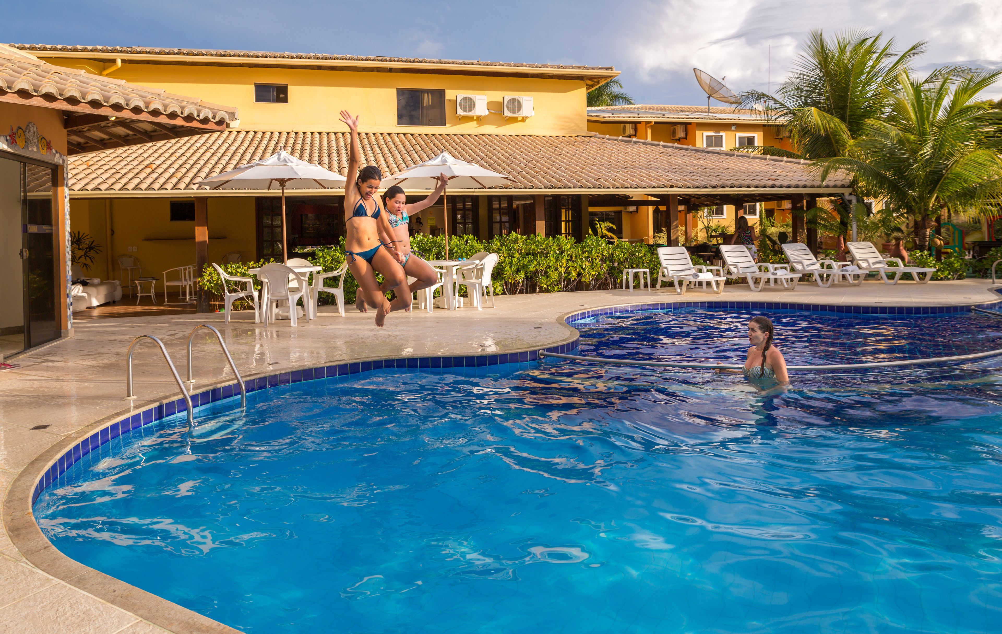 A swimming pool with a tiled edge, lounge chairs, and umbrellas.