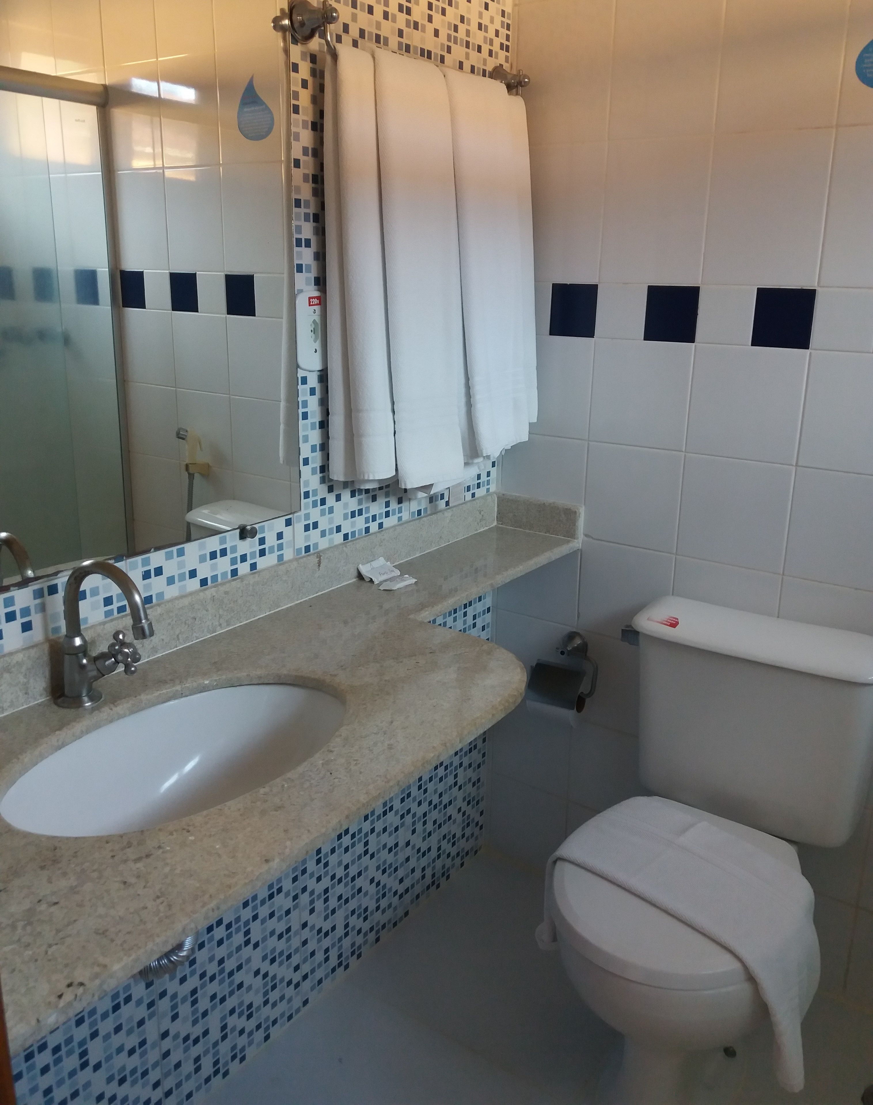 A bathroom with a sink, mirror, towel rack, toilet, and a shower.