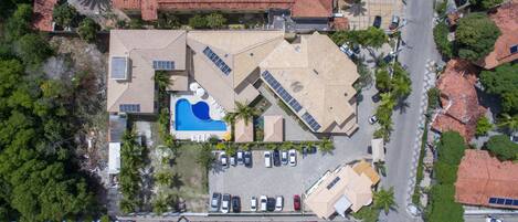 Vista aérea de una propiedad con piscina, varios espacios de estacionamiento y una combinación de edificios residenciales y comerciales.