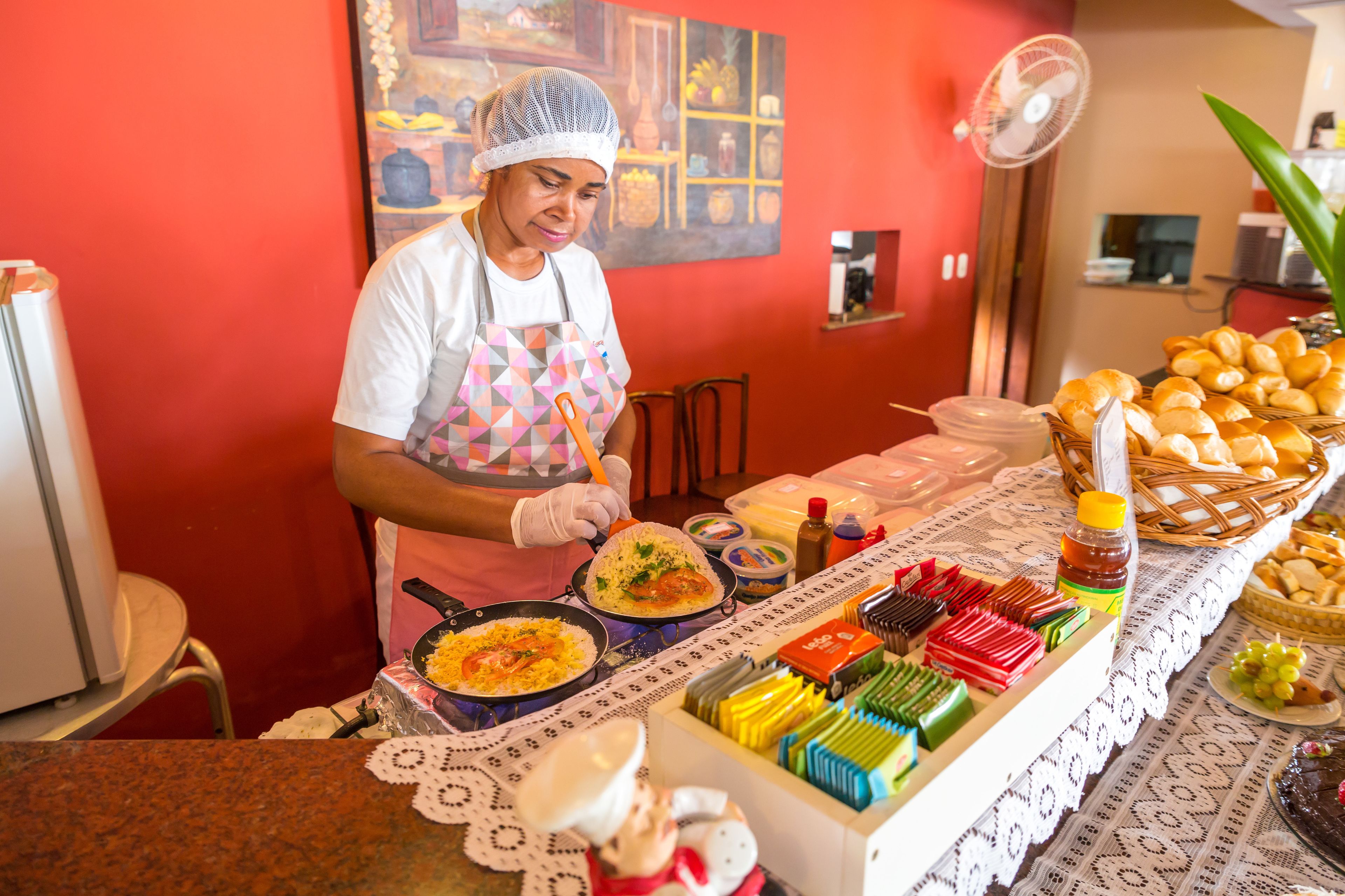 A buffet setup with various food items and a person serving food.