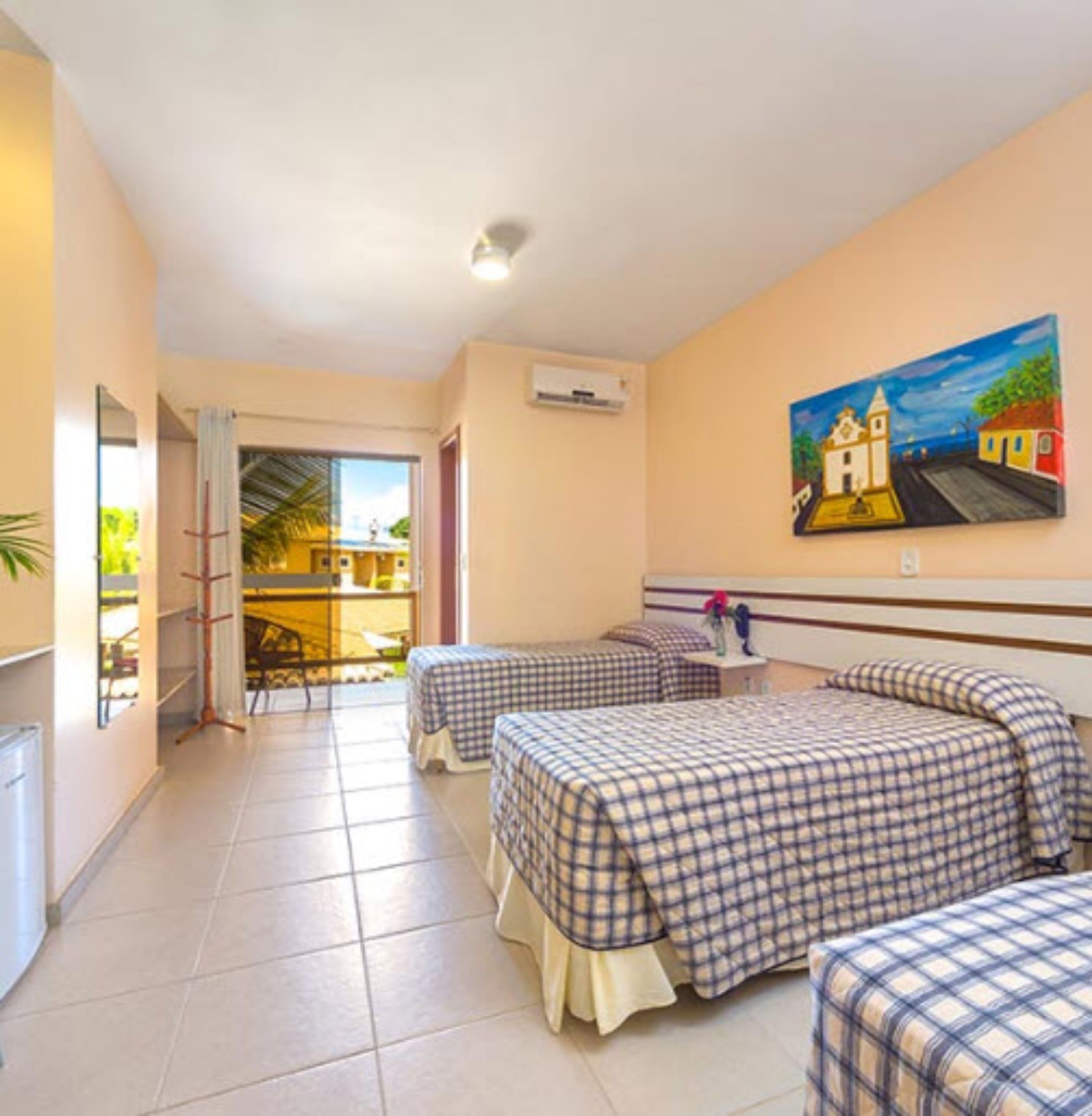 A hotel room with two beds, a painting on the wall, and a view of the outside.
