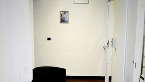 A hotel room with a brown carpet, a black sofa, a wooden bench, and a white door. - B&B Marbo Florence (Florence)