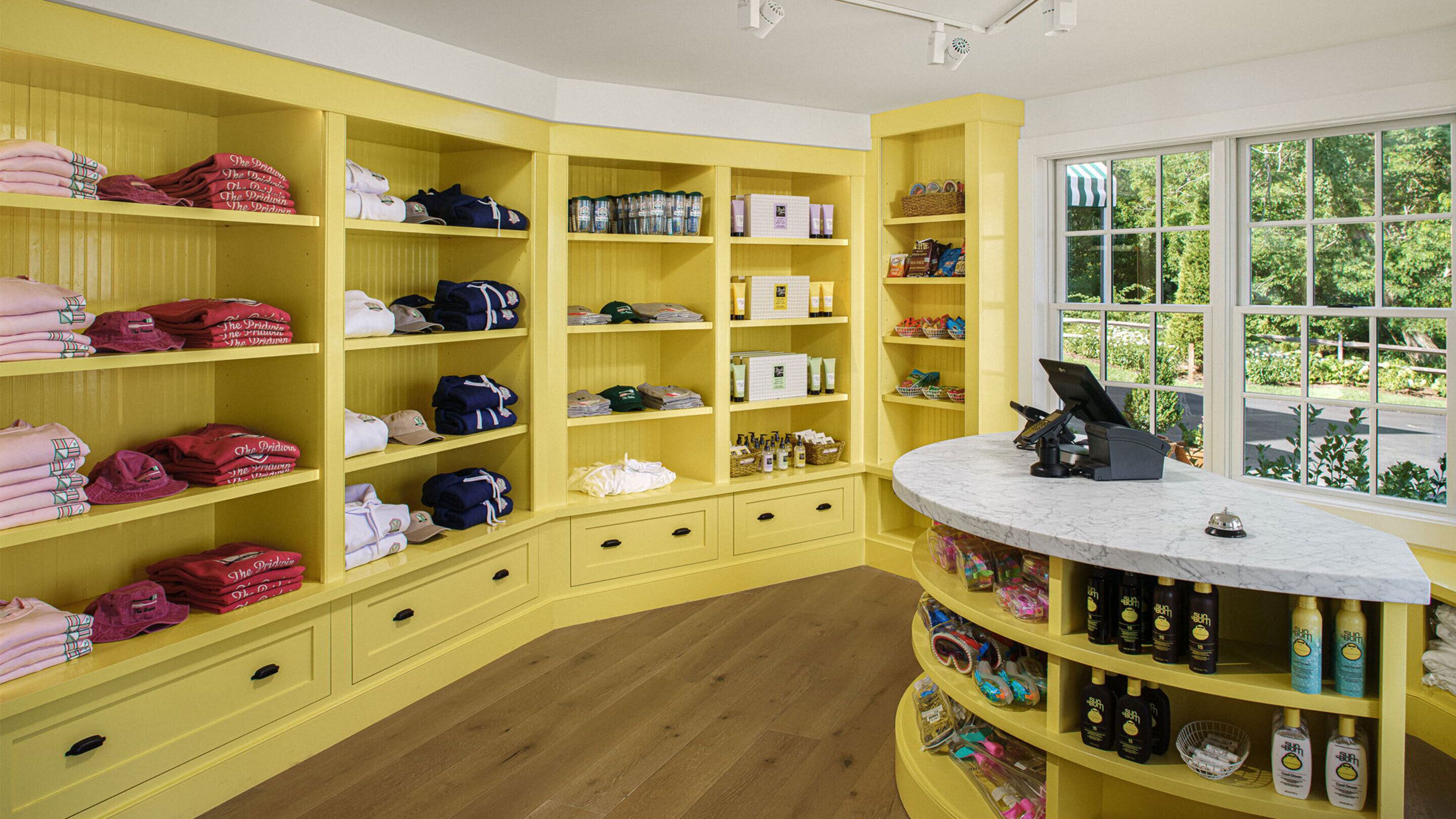 Een geel interieur met planken volop gevuld met opgevouwen kleding en toiletartikelen.