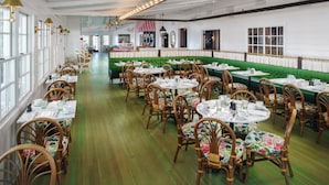En restaurang med gröna bås, trästolar och runda bord.