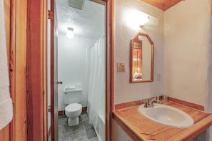A bathroom with a wooden vanity, a white sink, and a mirror.