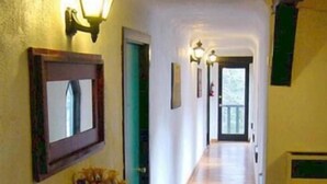 A hallway with a wooden floor, a green door, and a mirror on the left. - Amizette Inn and Restaurant (Taos Ski Valley)