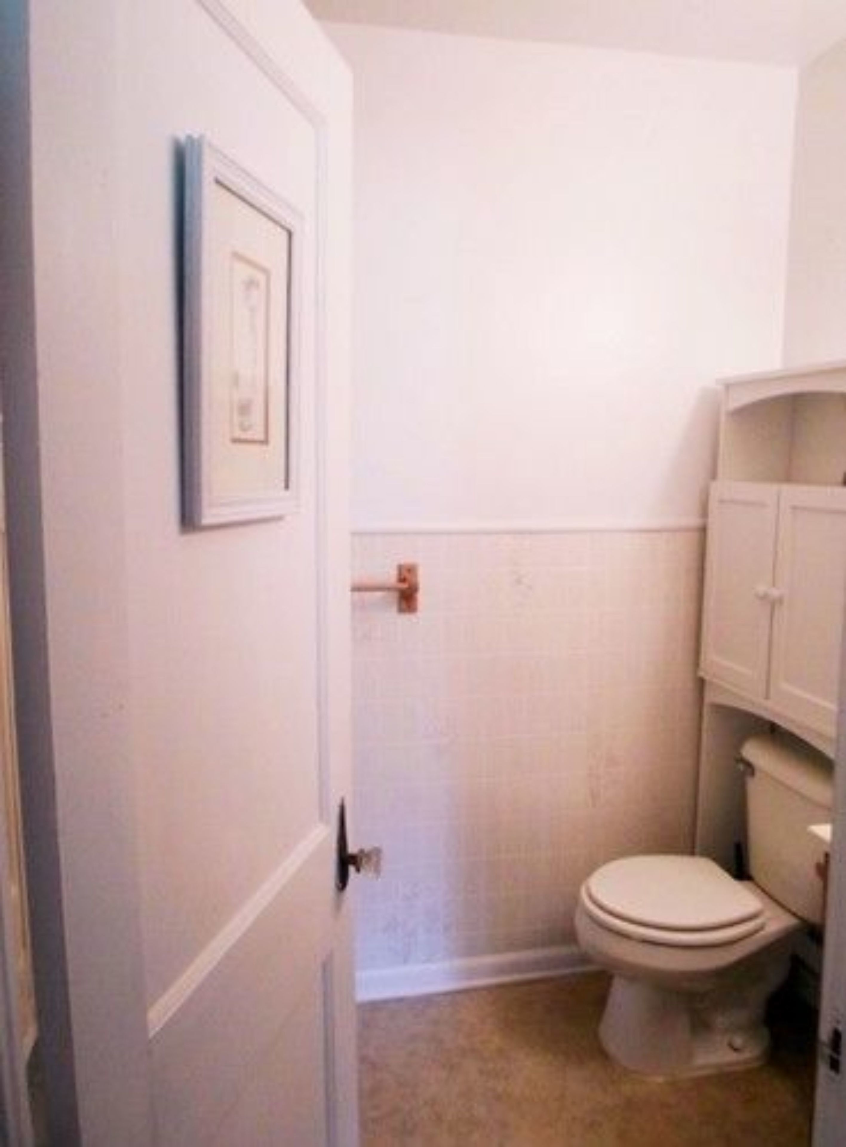 Un bagno piccolo e bianco con un water, un portasciugamani e un mobiletto.