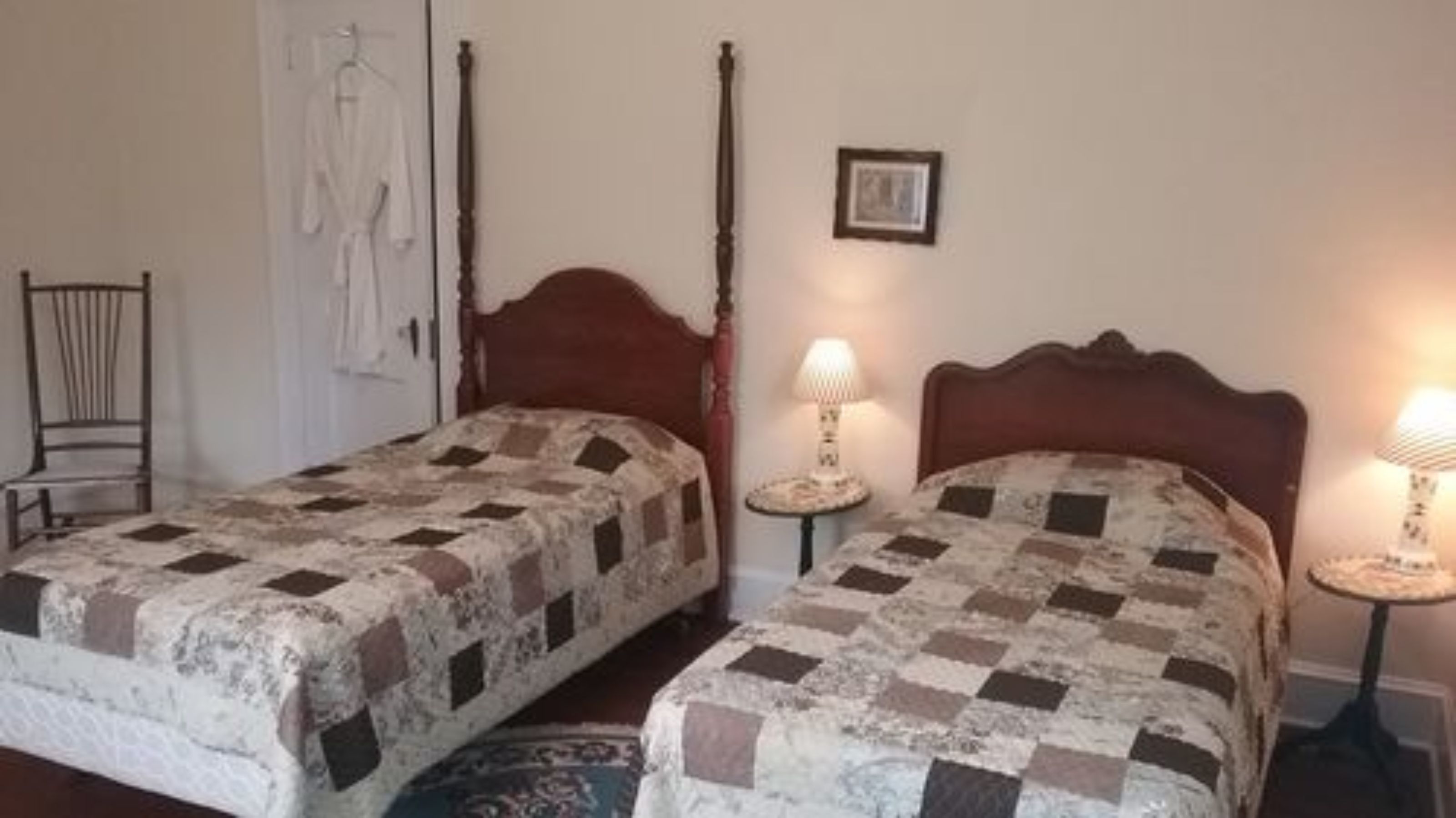 Two single beds with wooden headboards and a nightstand with a lamp between them.