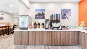 A modern reception area with a coffee station, a refrigerator, and a wall-mounted coffee machine.