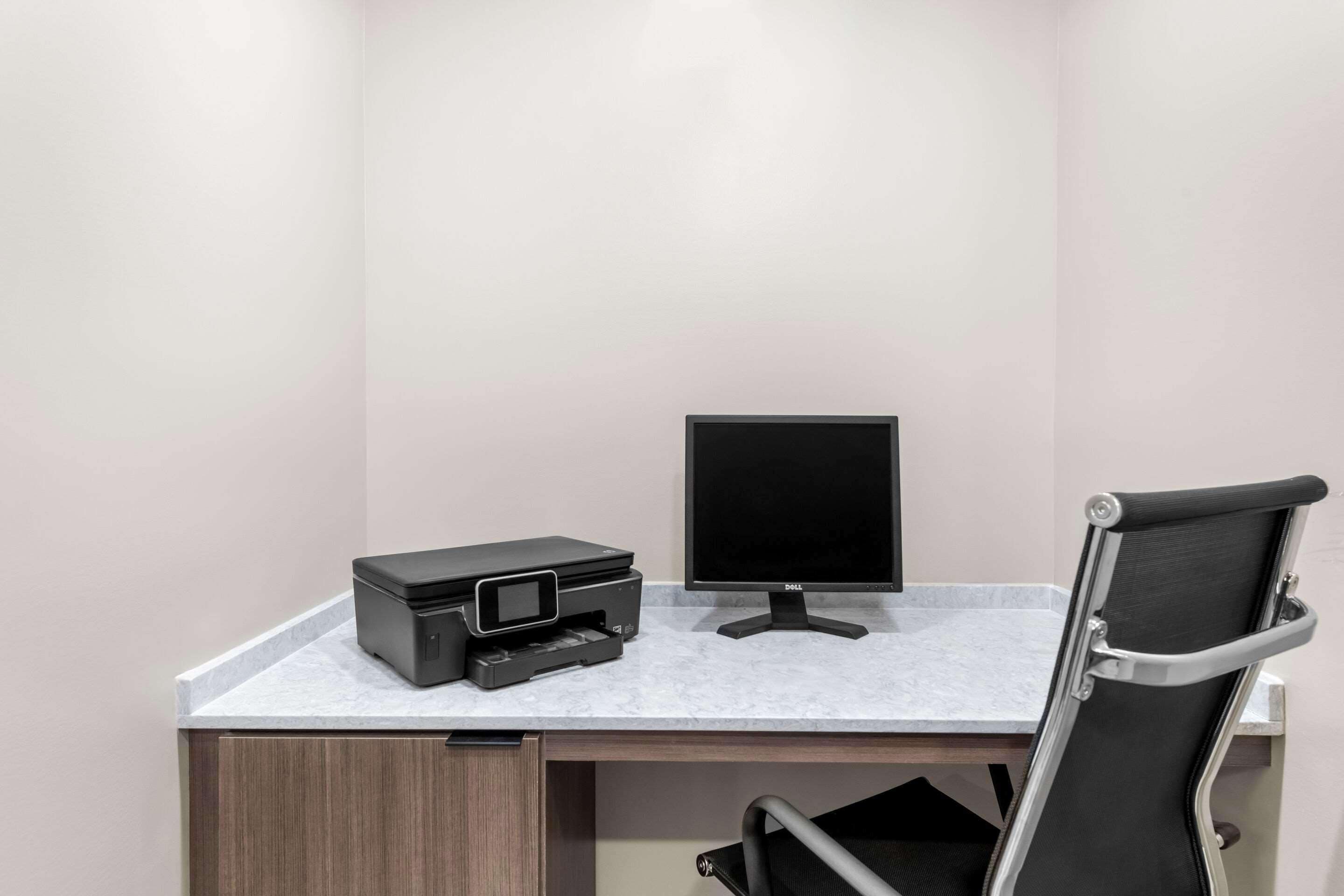Un bureau moderne, équipé d’une imprimante, d’un écran et d’une chaise.