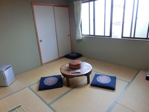 A tatami mat room with a tatami mat table, two cushions, a heater, and a sliding door. - Spa Inn Oyado Iguchi (Takayama)
