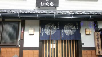 A traditional Japanese building with a wooden entrance, a sign above the door, and decorative hanging banners.