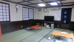 A traditional Japanese room with tatami flooring, a low wooden table, a larger table, a television, and a shoji screen. - Spa Inn Oyado Iguchi (Takayama)