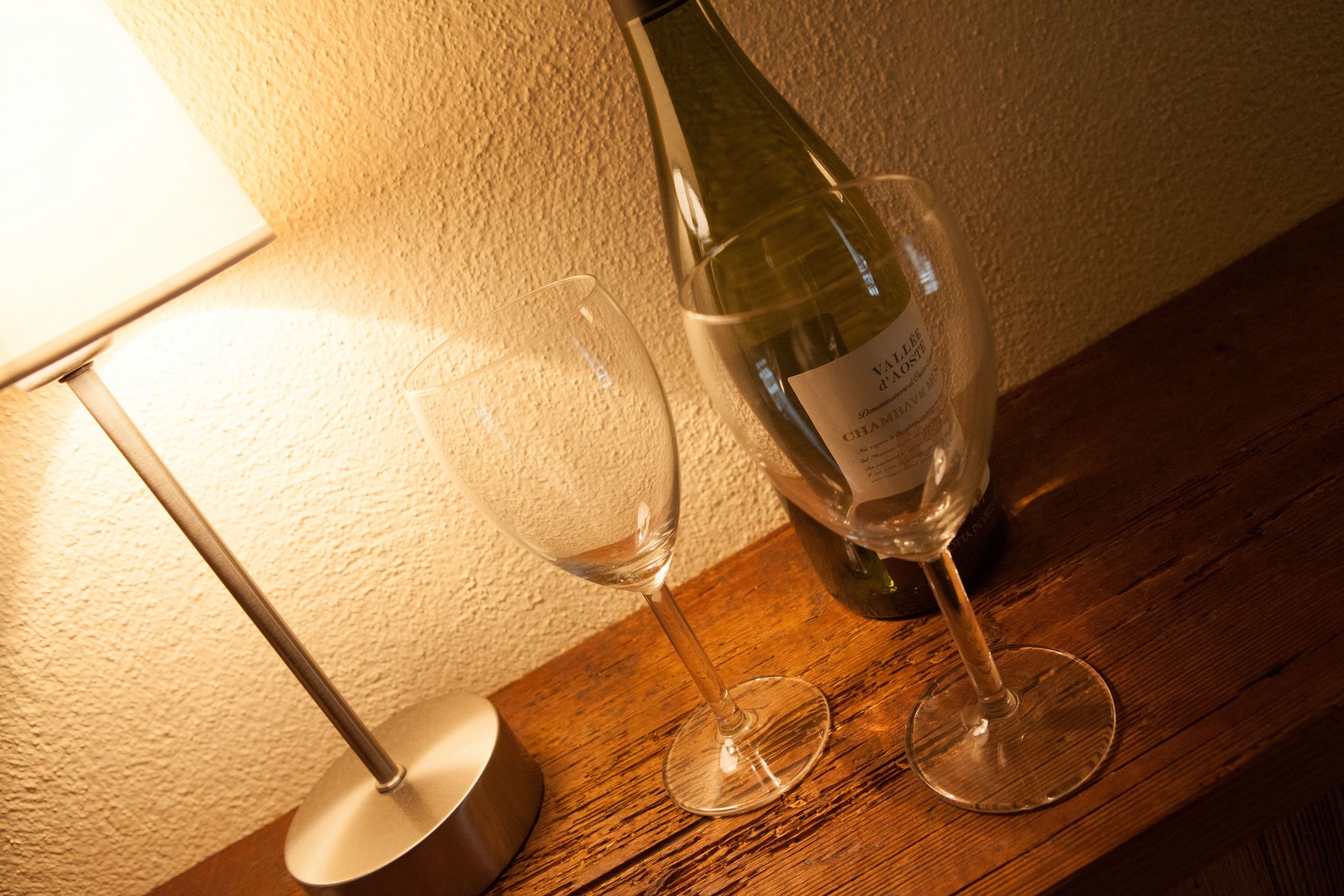 A bottle of wine and two glasses on a wooden surface.