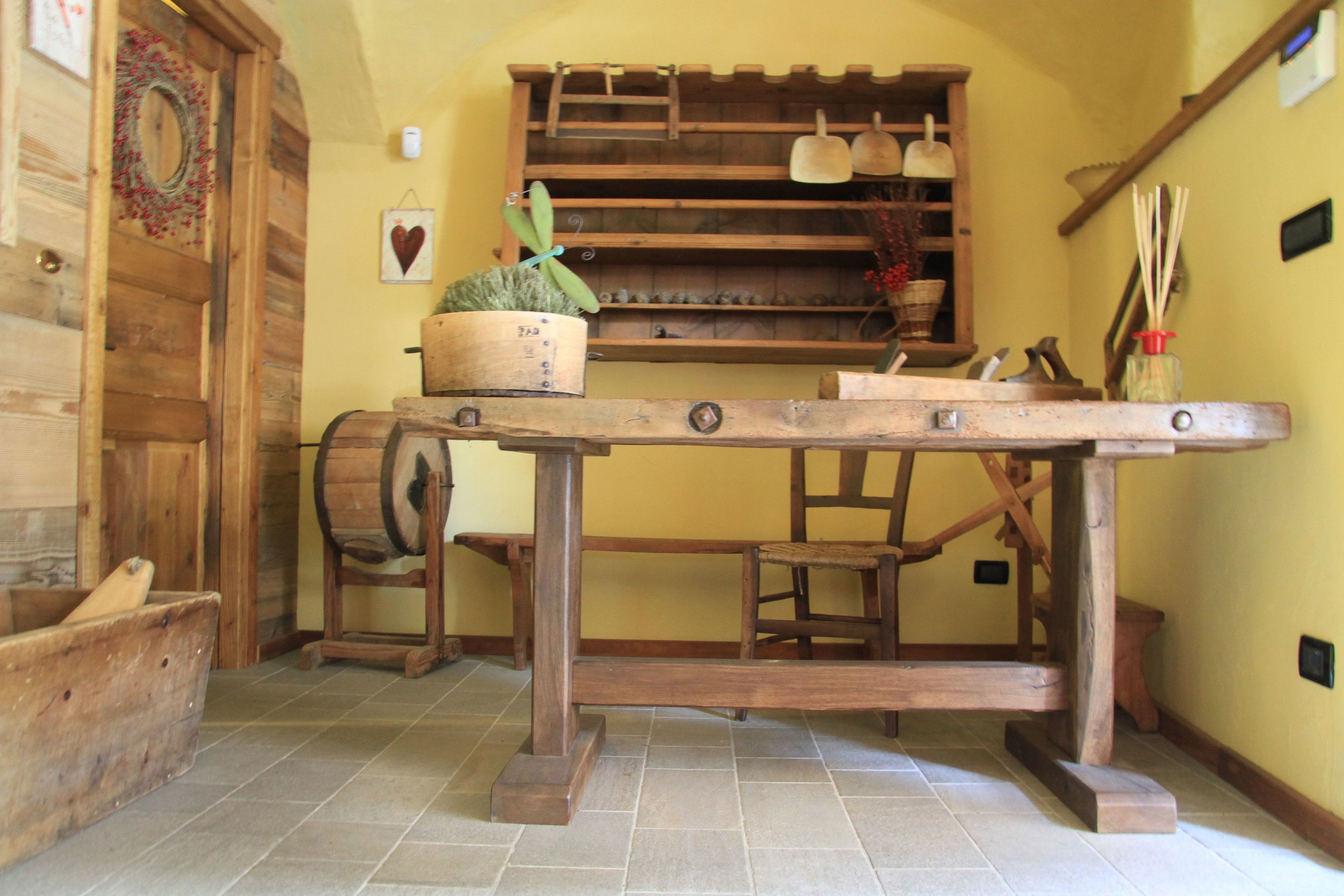 A rustic kitchen with wooden furniture, a barrel, and a shelf with kitchen utensils.