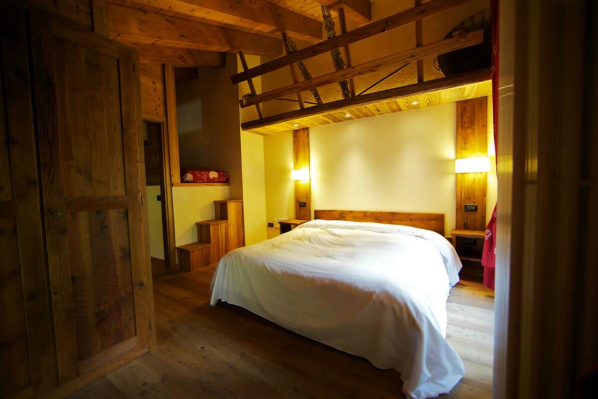 A bedroom with a wooden ceiling, a large bed, and two bedside lamps.