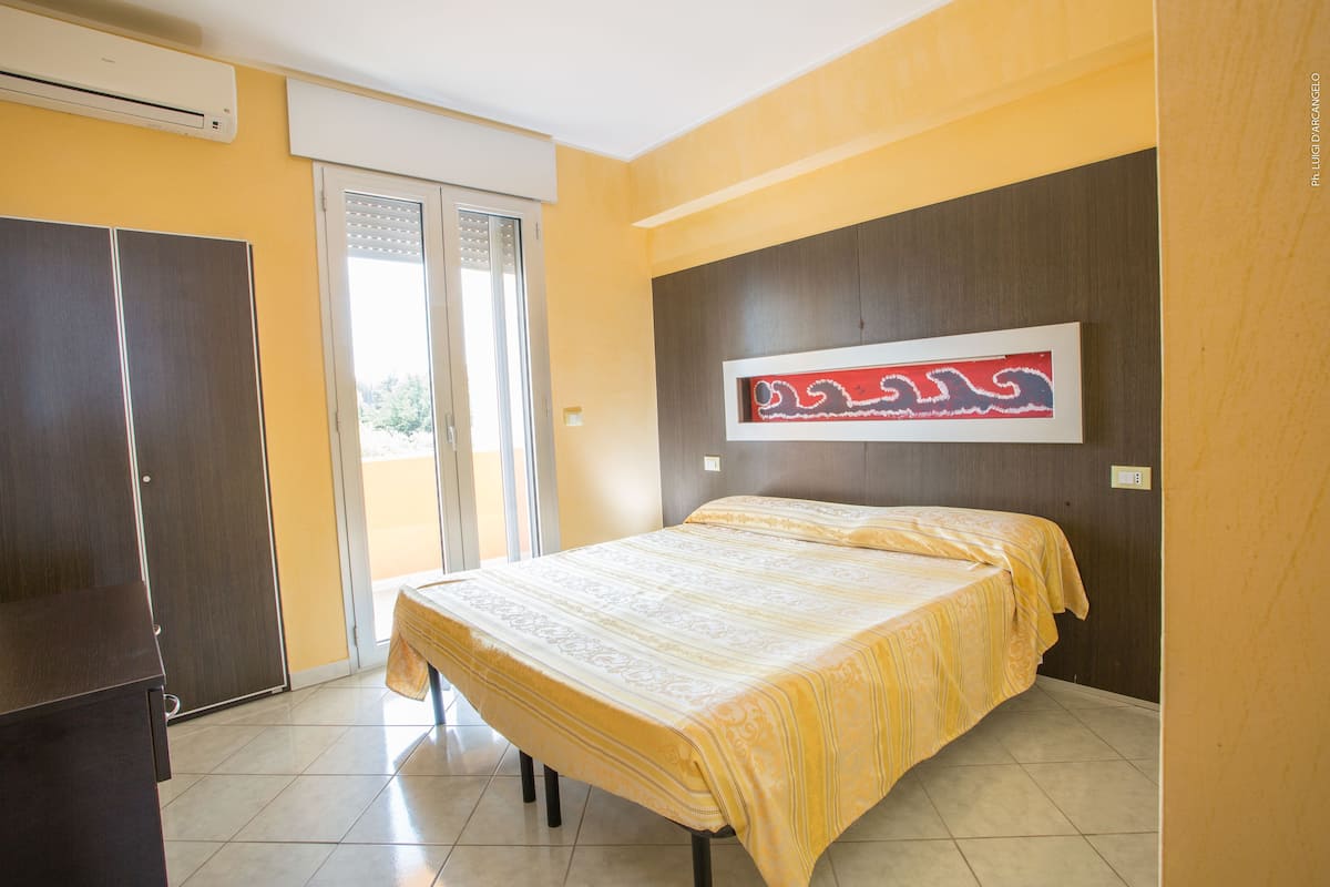 Une chambre à coucher comprenant un lit, une armoire et une porte-fenêtre coulissante donnant sur un balcon.