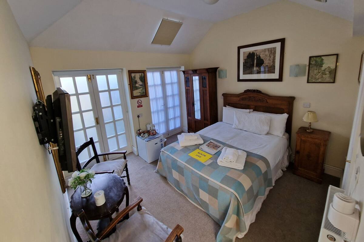 A bedroom with a bed, a desk, a chair, a radiator, and a window.