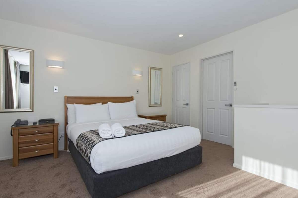 A neatly arranged bedroom with a bed, bedside tables, and a wardrobe.