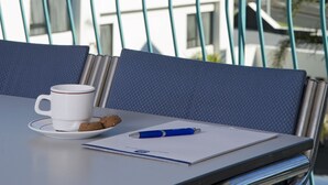 A balcony with a white table, a white cup, and a blue pen.