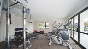A gym with exercise equipment, a weight bench, dumbbells, and a treadmill.