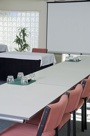 A conference room with a long table, chairs, a projector screen, and a potted plant. - Best Western Ellerslie International (Auckland)