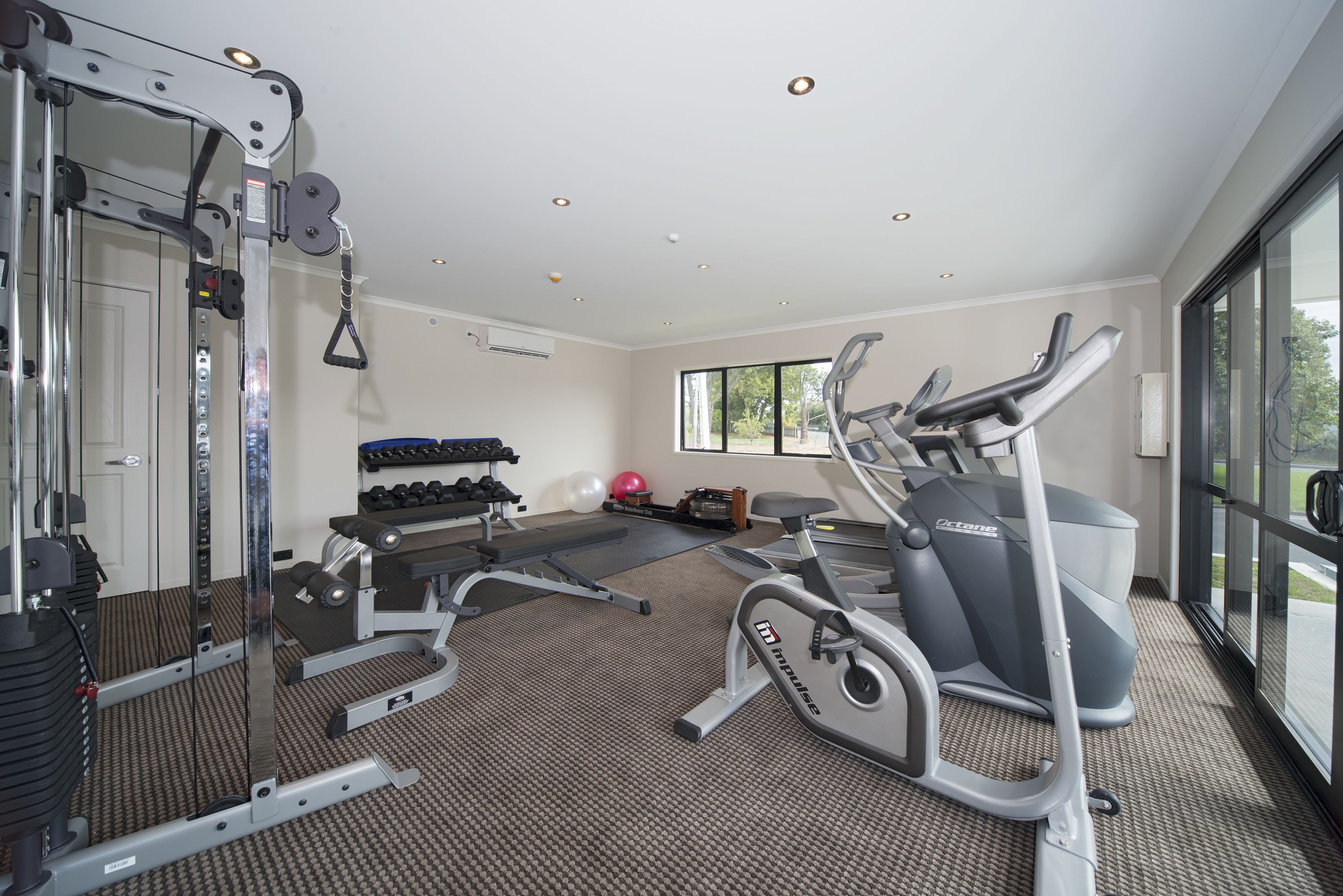 A gym with cardio equipment, weight machines, and dumbbells.
