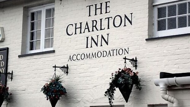 The exterior of The Charlton Inn, a white building with hanging flower baskets and a sign indicating it is an accommodation. - The Charlton Inn (Blandford Forum)
