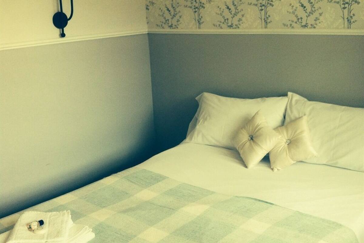 A neatly made bed with a checkered bedspread, white pillows, and a folded towel on the side.