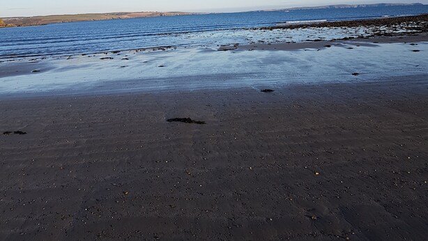Una playa con cielo despejado y agua tranquila.