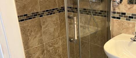 A bathroom with a glass-enclosed shower, a white sink, and a toilet.