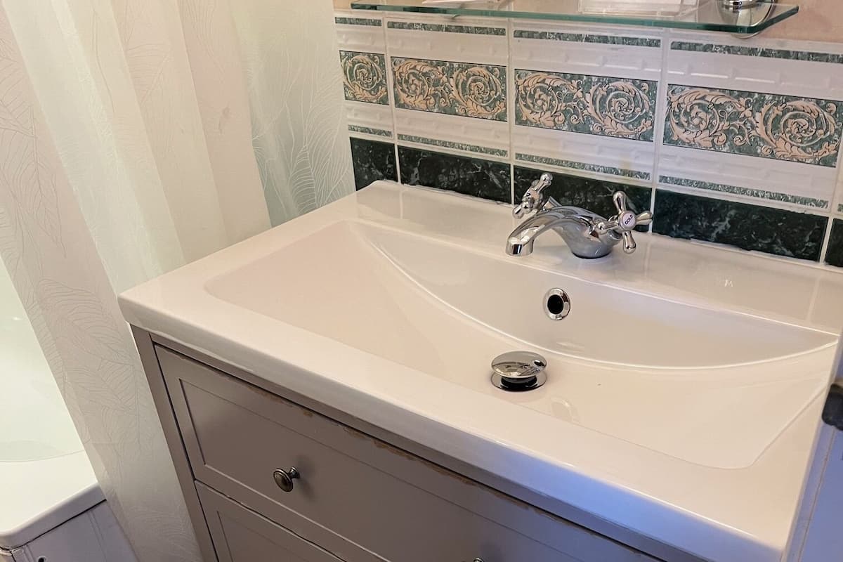Un baño con un lavabo color beige, un espejo y un mueble tocador con cajones.