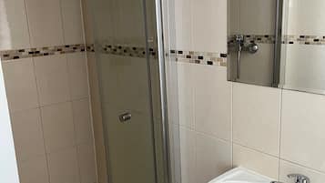A bathroom with a glass-enclosed shower, a white sink, and a mirror above the sink.