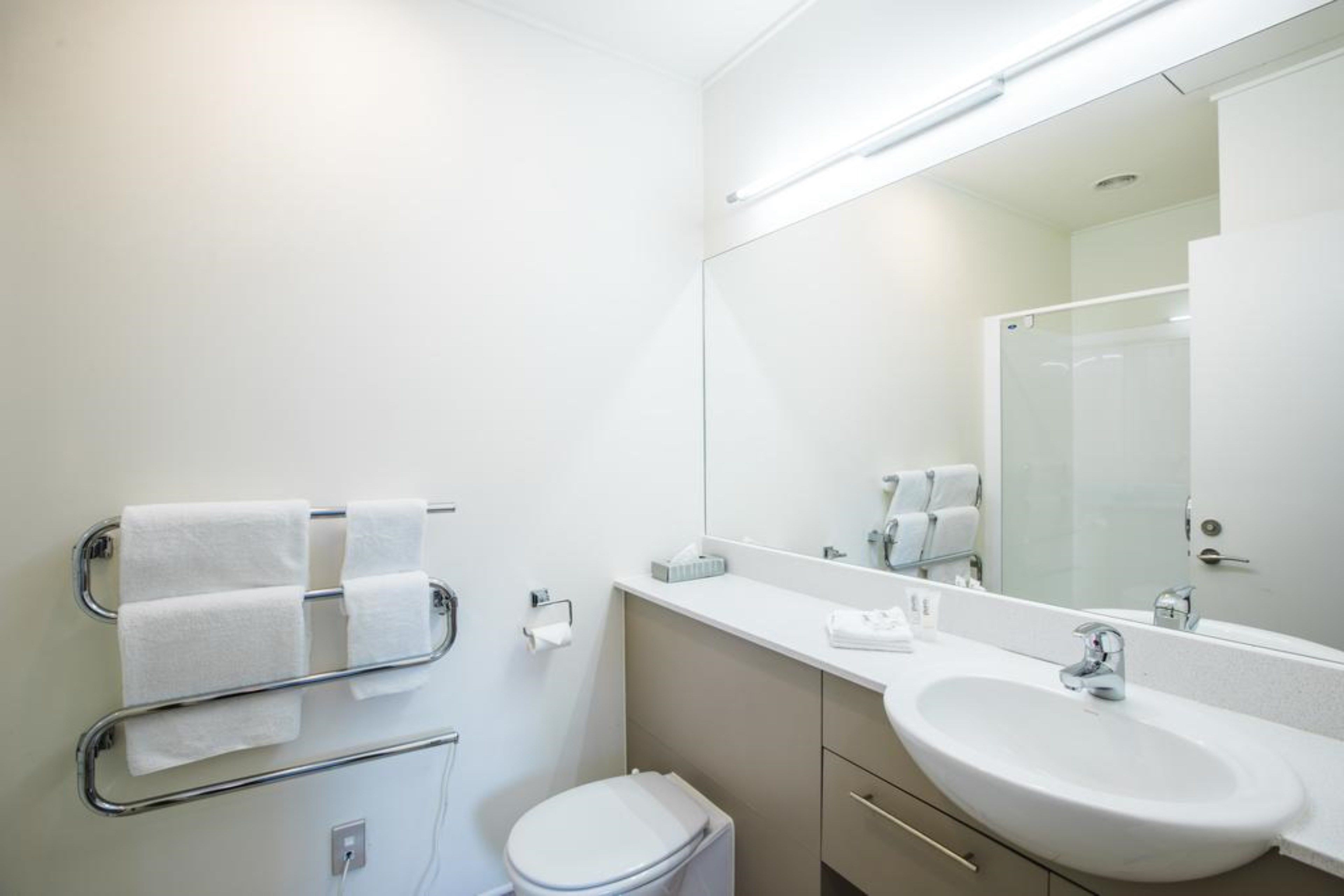 Une salle de bain moderne avec un lavabo blanc, un miroir et un porte-serviettes.
