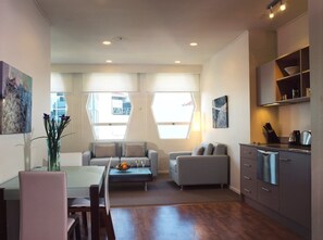 A modern living room with a dining area, a kitchen, and large windows. - Quest on Lambton (Wellington)