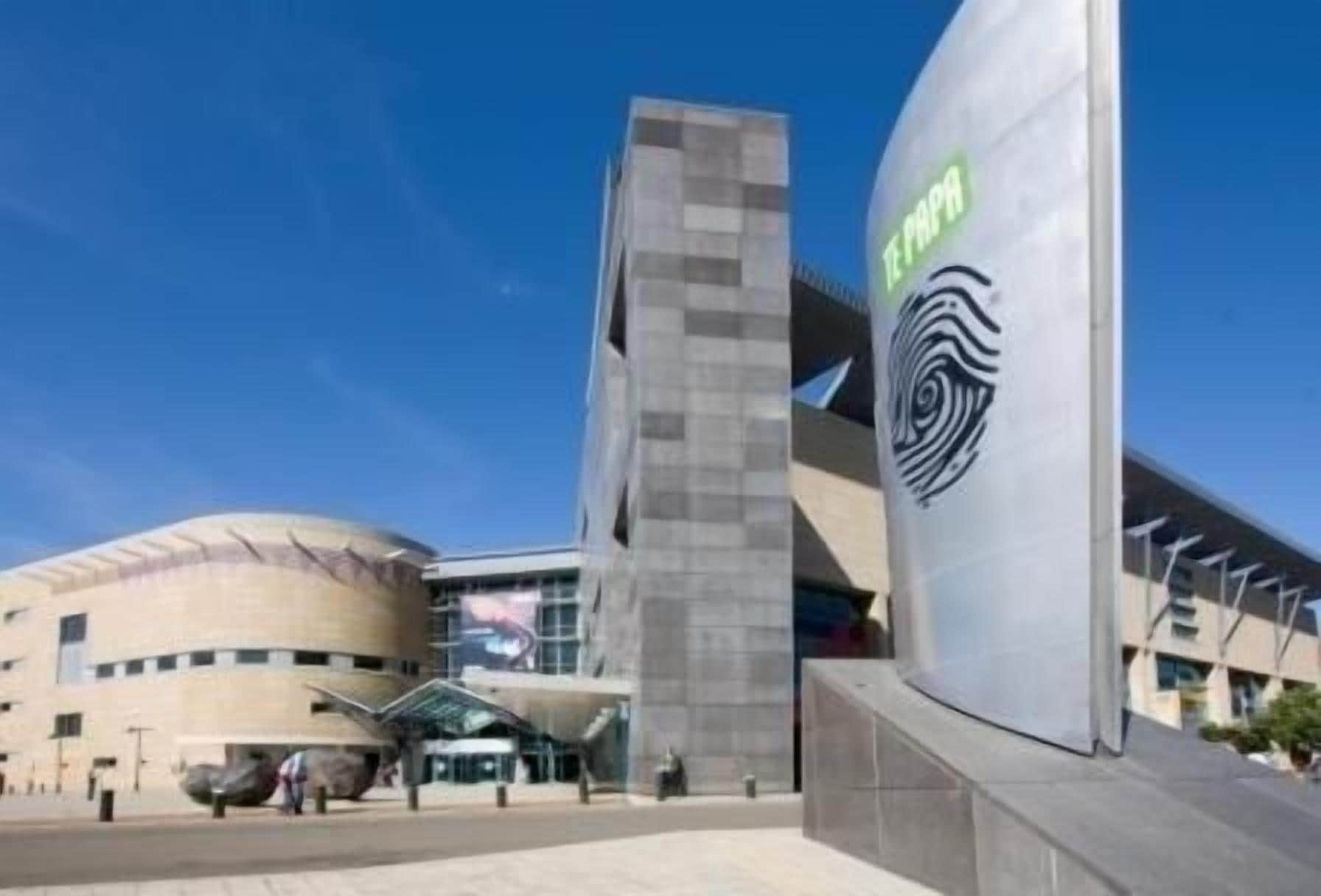 A modern building with a prominent circular structure and a tall vertical element with a spiral design.