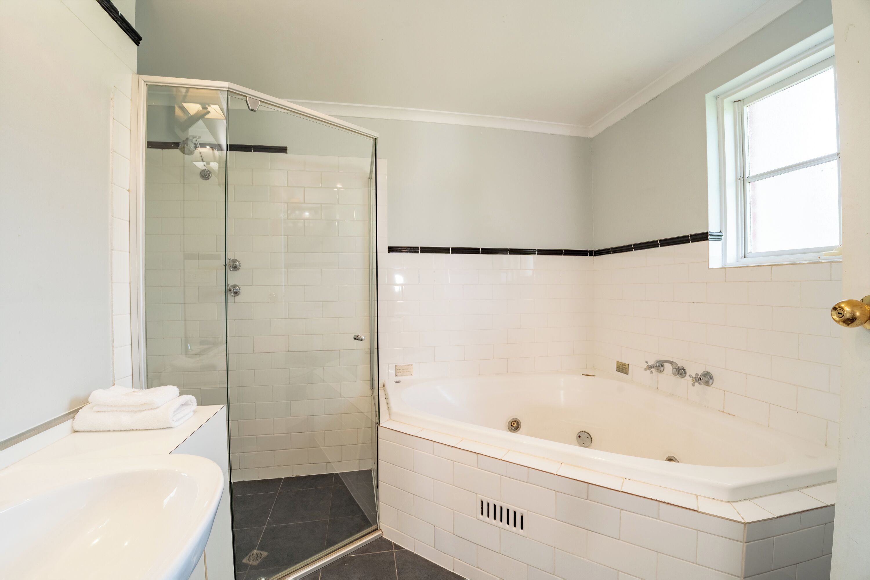 A bathroom with a glass-enclosed shower, a white bathtub, and a sink.