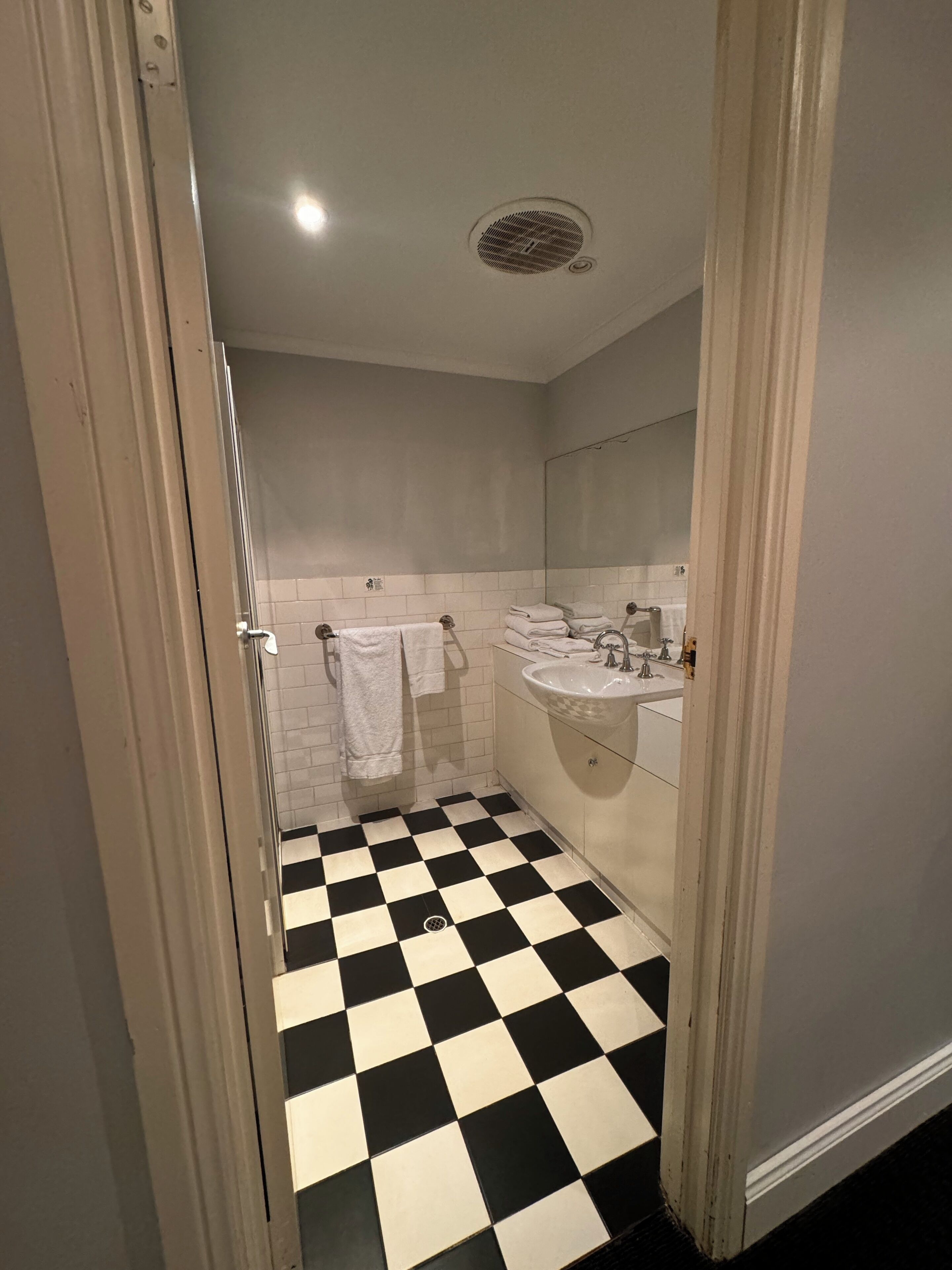 A bathroom with a black and white checkered floor, a sink, and a mirror.