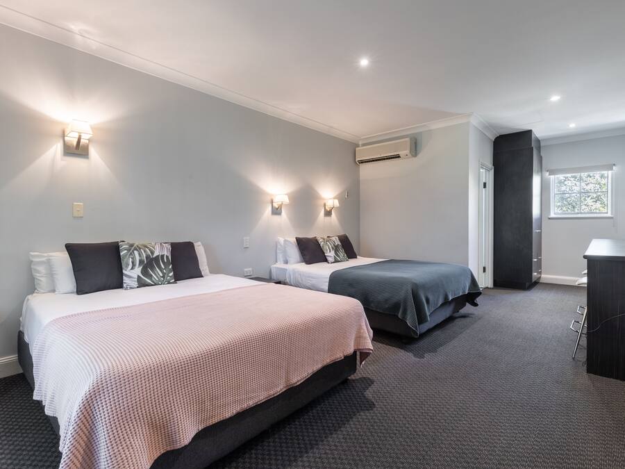 Una habitación de hotel con dos camas, un escritorio y una ventana.