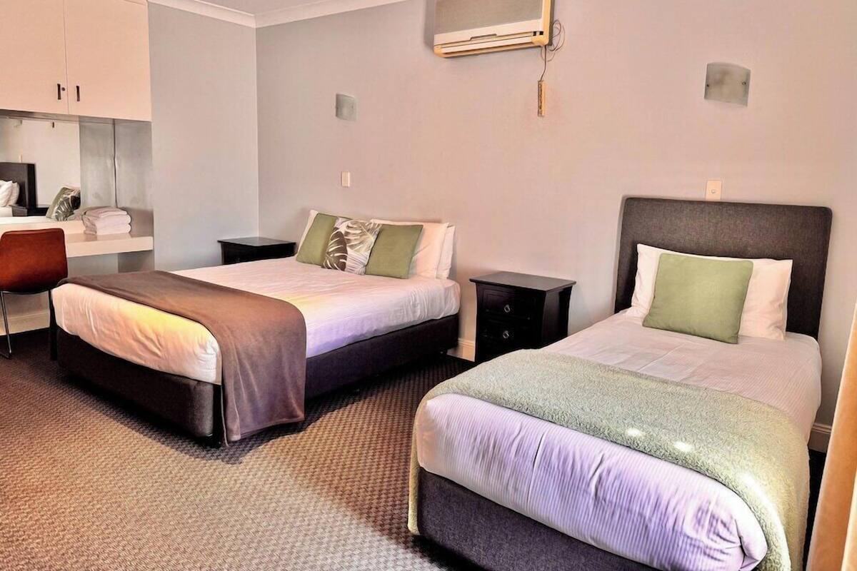 A hotel room with two beds, a desk, and a wardrobe.