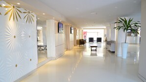 A spacious, modern hotel lobby with a polished floor, a reception desk, seating area, and a large potted plant. - Beira Mar Hotel (Aracaju)