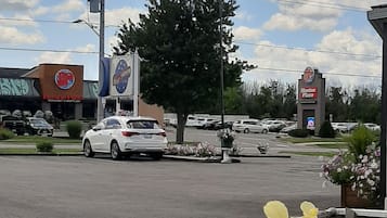 En parkeringsplats med en pizzeria, ett stort träd och en flagga.