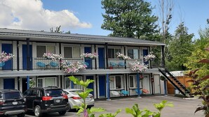 Un motel con una estructura de dos pisos, un estacionamiento y una escalera que lleva al nivel superior.