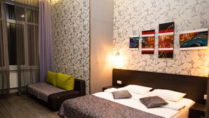 Et hotelværelse med to senge, en sofa og et vindue med gardiner.